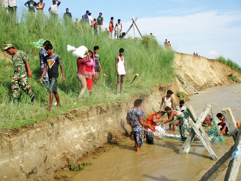 Nepal Army and Nepal Police personnel along with locals prepare to make an embankment to stop Kamala River from eroding the land in Siraha district, on Friday, July 29, 2016. Photo: RSS