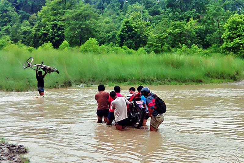 Locals carry a motorcycle putting their lives on stake across the swollen Anaukhi River in Kanchanpur district, on Monday, July 25, 2016. Photo: RSS
