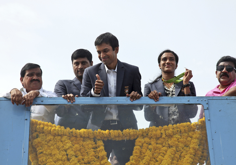 Pusarla Sindhu, second from right, one of the only two Indians to win medals at the just concluded Rio Olympics, displays her silver medal as she is brought home in a procession along with her coach Pullela Gopichand, third from left, upon their arrival at Hyderabad, India, Monday, August 22, 2016. Photo: AP