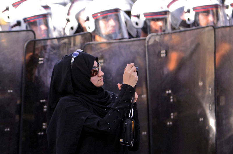 FILE- An anti-government protester stands in front of riot police while photographing other demonstrators in Manama, Bahrain, on January 18, 2012. Photo: AP