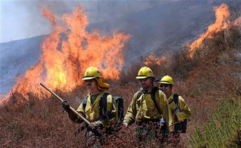 Firefighters battle the Bluecut Fire along Swarthout Canyon Road in the Cajon Pass, north of San Bernardino, California, on Tuesday, August 16, 2016. Photo: The Sun via AP