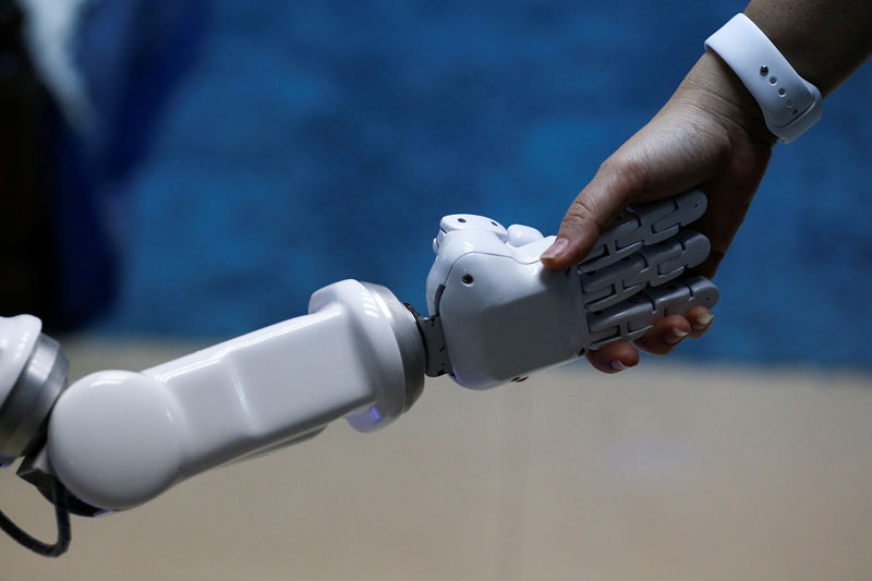 Chalermpon Punnotok, CEO of CT Asia Robotics gives a hand to a robot during an interview with Reuters in Bangkok, Thailand, on July 5, 2016. Photo: Reuters