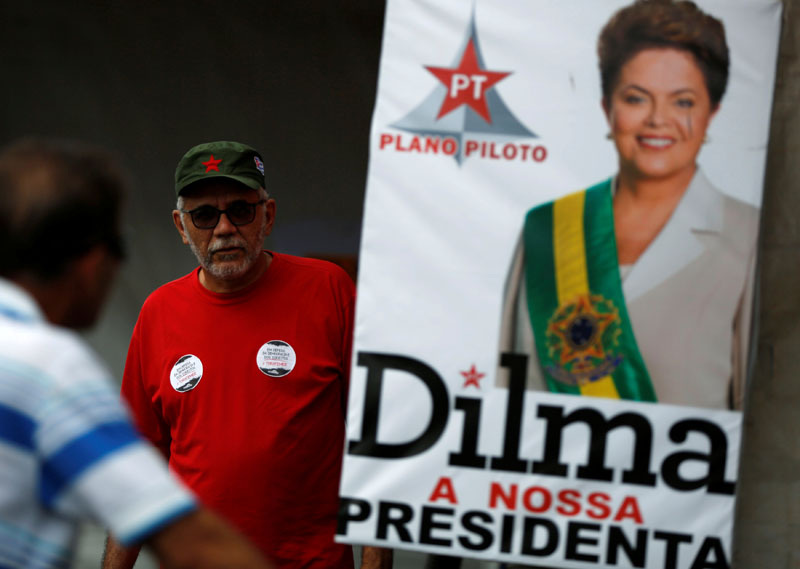 People walk next to an official photo of Brazil's suspended President Dilma Rousseff, at a camp in support of Rousseff, in Brasilia, Brazil, on August 28, 2016. Photo: Reuters