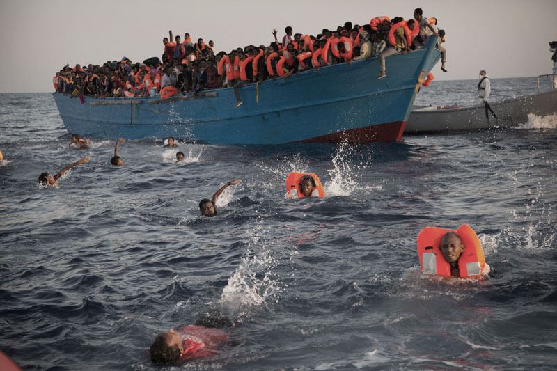 Migrants, most of them from Eritrea, jump into the water from a crowded wooden boat as they are helped by members of an NGO during a rescue operation at the Mediterranean sea, about 13 miles north of Sabratha, Libya on Monday, August 29, 2016. Photo: AP