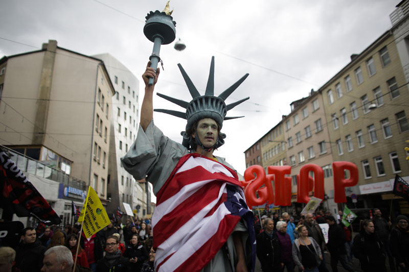 FILE -  A  man walking on stilts and dressed like the Statue of Liberty attends a protest  against the planned Transatlantic Trade and Investment Partnership, TTIP, ahead of the visit of United States President Barack Obama in Hannover, Germany, on April 23, 2016. Photo: AP