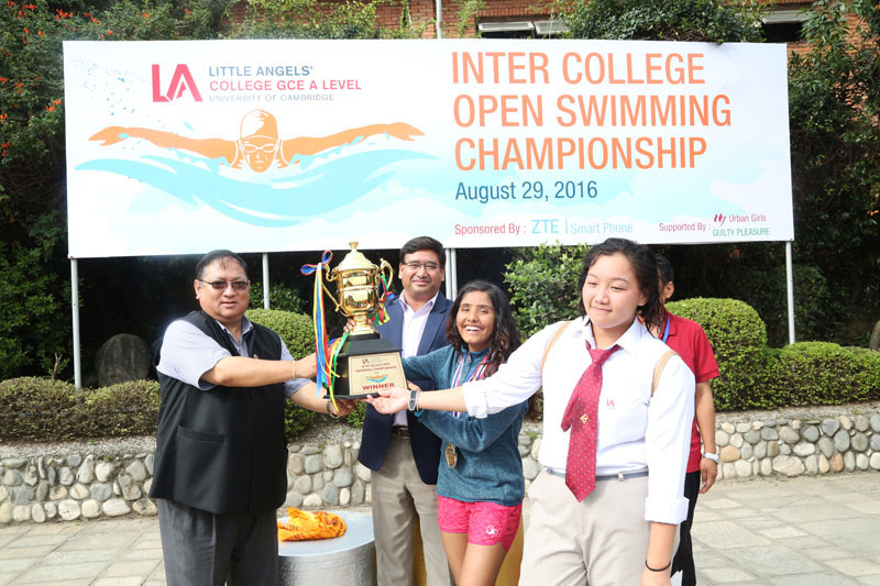 Jeevan Ram Shrestha, President of Nepal Olympic Committee and Founder Chairman of Little Angelsu2019 Umesh Shrestha handing over the trophy to LA team members after the Inter-college Swimming Championship on Tuesday. Photo: THT