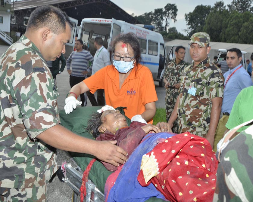 Nepal Army personnel transferring an injured person to an ambulance from a helicopter. 
