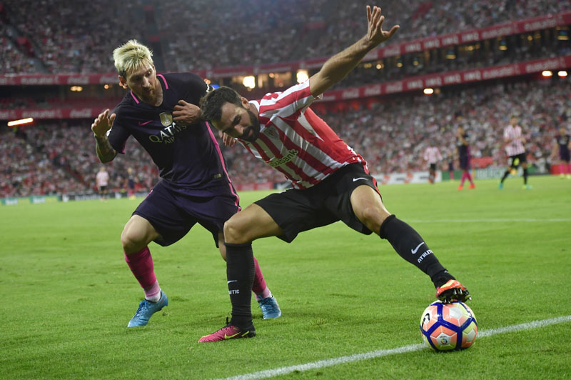 FC Barcelona's Lionel Messi (left) duels for the ball with Athletic Bilbao's Mikel Balenziaga during the Spanish La Liga soccer match between FC Barcelona and Athletic Bilbao, at San Mames stadium, in Bilbao, northern Spain, on Sunday, August 28, 2016. FC Barcelona won the math 1-0.  Photo: AP