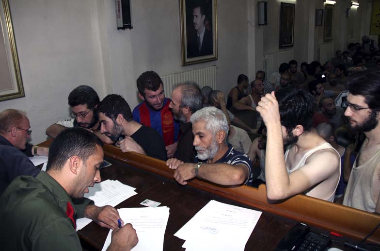 File- Syrian prisoners sign their papers of release at the Damascus Police Command headquarters in Damascus, Syria, on September 1, 2012. Photo: AP