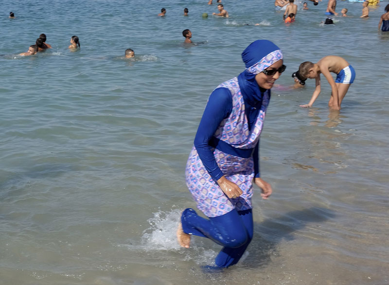 A woman wearing a burkini walks in the water August 27, 2016 on a beach in Marseille, France, the day after the country's highest administrative court suspended a ban on full-body burkini swimsuits that has outraged Muslims and opened divisions within the government, pending a definitive ruling. Photo: REUTERS