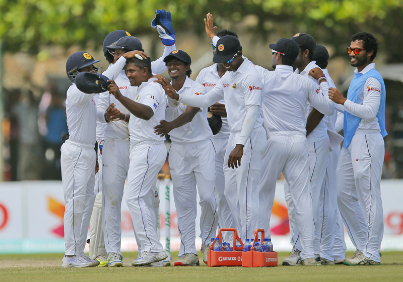 Members of Sri Lankan team congratulate bowler Rangana Herath, second left, for taking a hat trick dismissing Australia's Mitchell Starc on day two of their second test cricket match in Galle, Sri Lanka, Friday, August 5, 2016. Photo: AP