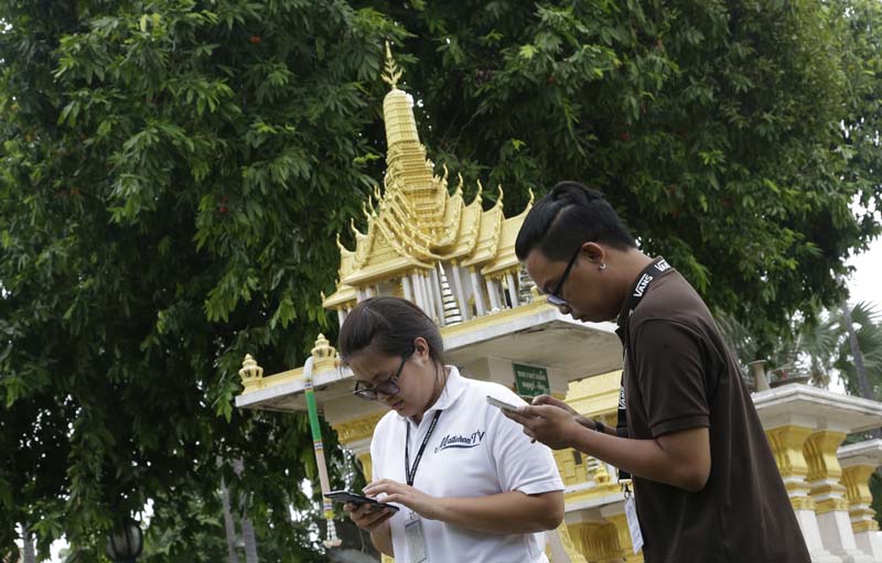 Thai reporters play Pokemon Go on their phone in front of a spirit house at a Government building in Bangkok, Thailand, on Monday, August 8, 2016. Photo: AP