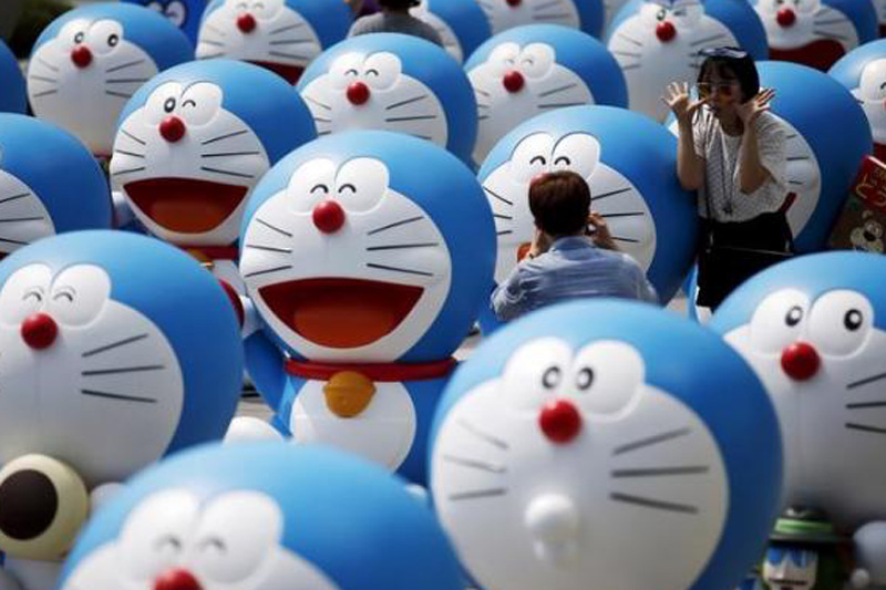 A man takes photographs of his girlfriend posing next to a Doraemon figure during an exhibition in Seoul, South Korea, August 31, 2015. Photo: Reuters