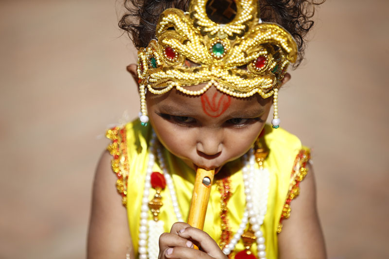 A boy dressed as the Hindu God Krishna plays a flute in front of the Krishna Temple in Patan of Lalitpur, on the occasion of Krishna Janmashtami festival, on Thursday, August 25, 16. Photo: Skanda Gautam