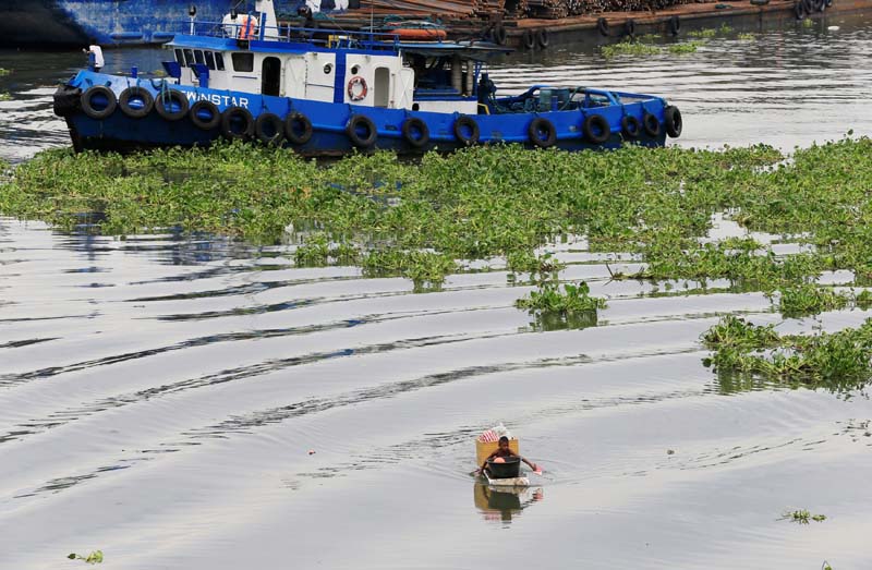 A tugboat passes a boy as he wades through a polluted river using a makeshift raft made of styrofoam to collect reusable items at a Manila bay in Baseco, Tondo city, metro Manila, Philippines on August 1, 2016. Photo: Reuters