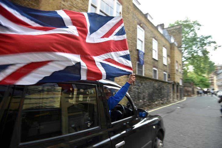 A taxi driver holds a Union flag, as he celebrates following the result of the EU referendum, in central London, Britain June 24, 2016.    REUTERS/Toby Melville/Files