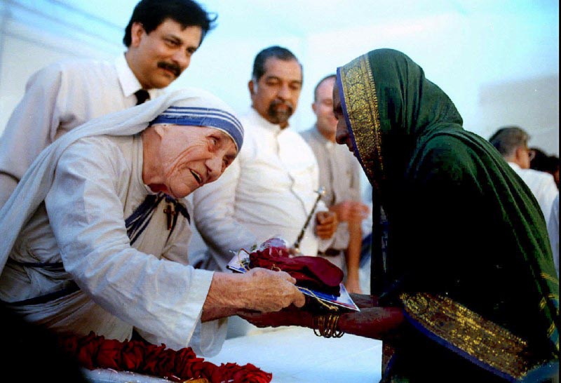 Mother Teresa presents documents for a new house to a villager from Latur in Bombay on September 26, 1994. REUTERS/Savita Kirloskar