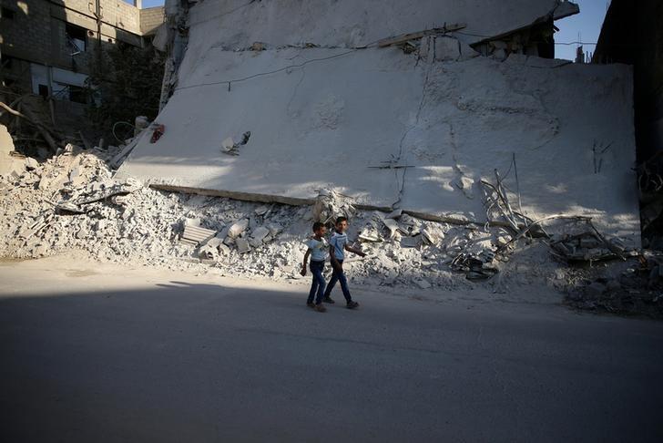 Boys walk near a damaged building on the first day of Eid al-Adha celebrations in the rebel held Douma neighbourhood of Damascus, Syria September 12, 2016. REUTERS/Bassam Khabieh