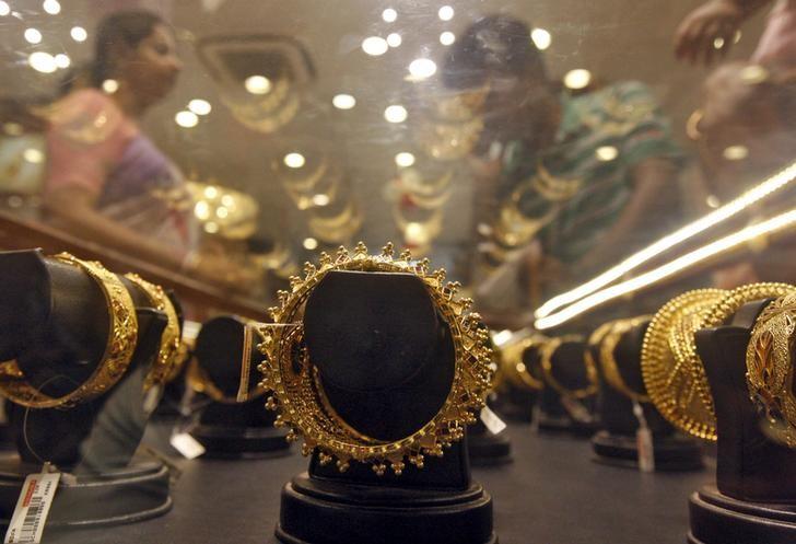 Gold bracelets are on display as a woman (L) makes choices at a jewellery showroom on the occasion of Akshaya Tritiya, a major gold buying festival, in Kolkata April 21, 2015.  REUTERS/Rupak De Chowdhuri/Files