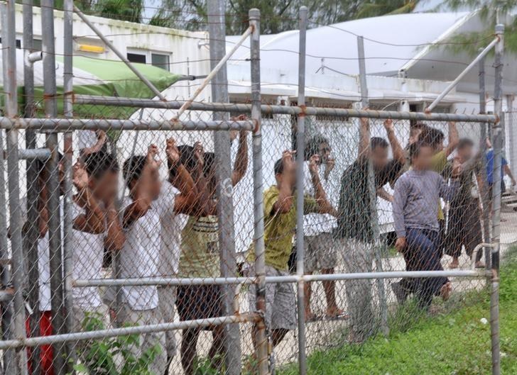 Asylum-seekers look through a fence at the Manus Island detention centre in Papua New Guinea March 21, 2014. AAP/Eoin Blackwell/via REUTERS