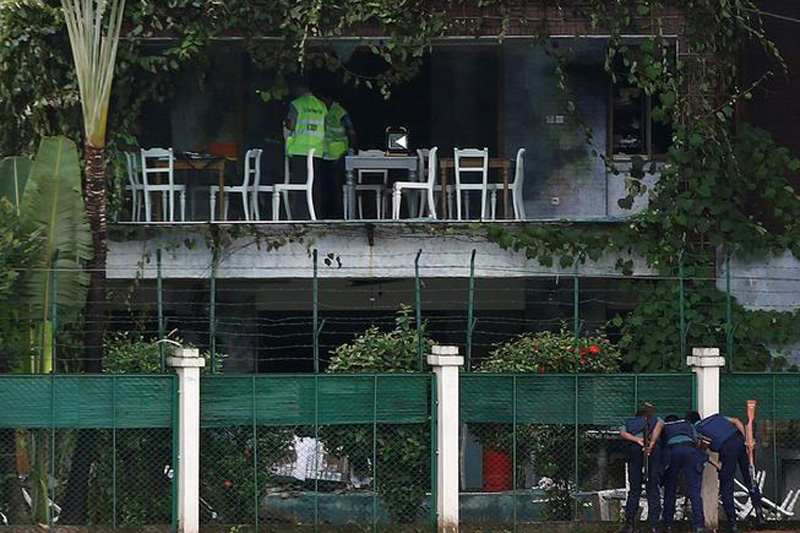 Policemen sneak a look inside the Holey Artisan Bakery and the O'Kitchen Restaurant as others inspect the site after gunmen attacked, in Dhaka, Bangladesh, July 3, 2016. Photo: Reuters