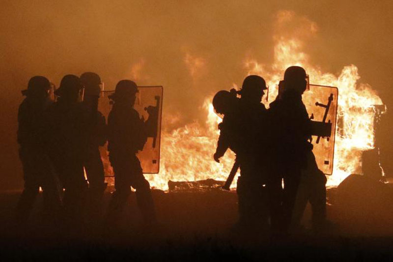 French CRS police are in silhouette as they pass flames on the eve of the evacuation and transfer of migrants to reception centers in France, and the dismantlement of the camp called the 'Jungle' in Calais, France, on October 23, 2016. Photo: Reuters
