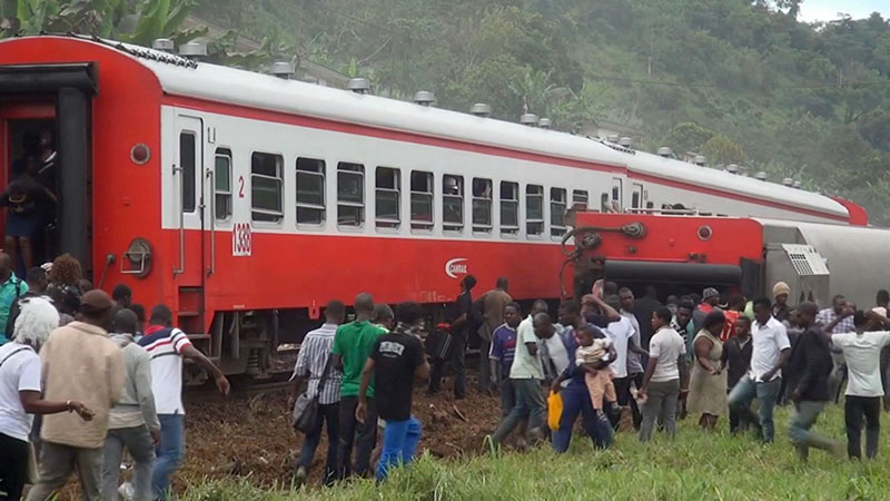 People walk beside a derailed train carriage after an accident in Eseka, Cameroon, on Friday, October 21, 2016. Cameroon's transport minister says at least 53 people have died after a train overloaded with passengers derailed along the route that links the country's two major cities. Photo: videograb Equinox TV via AP