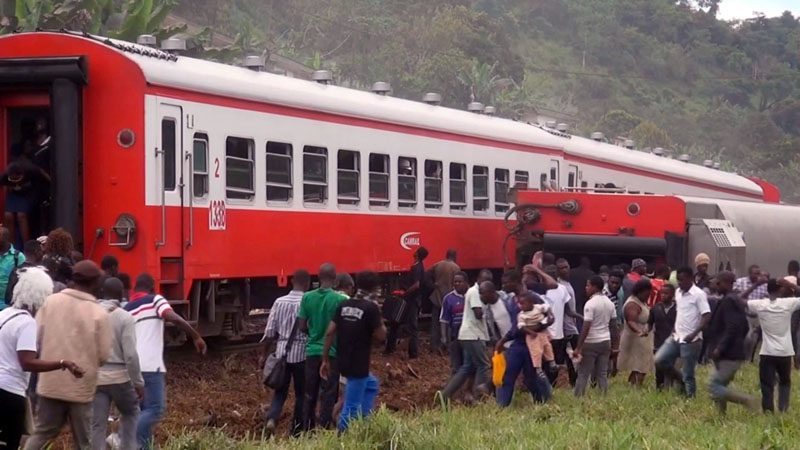 In this image made from video, people walk beside a derailed train carriage after an accident in Eseka, Cameroon, Friday, on October 21, 2016. Cameroon's transport minister says at least 53 people have died after a train overloaded with passengers derailed along the route that links the country's two major cities. Photo: Equinox TV via AP