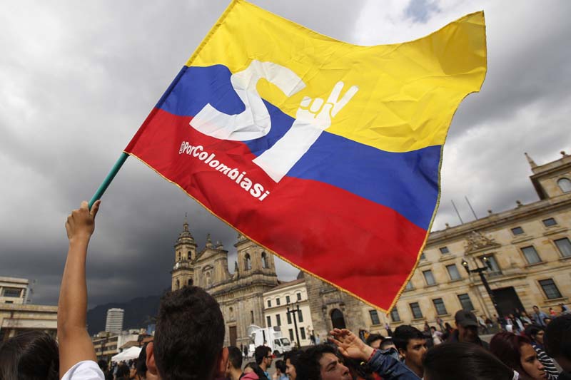 A supporter of the peace deal signed between the Colombian government and rebels of the Revolutionary Armed Forces of Colombia, FARC, wave a flag during a rally in front of Congress, in Bogota, Colombia, on Monday, October 3, 2016. Photo: AP