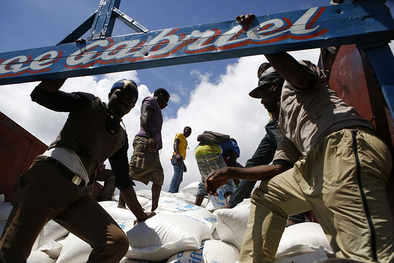 Workers load sacks of rice onto a truck after they were delivered by US military helicopter, in the mountain village of Beaumont, near Jeremie, Haiti, on Thursday, October 13, 2016. Photo: AP