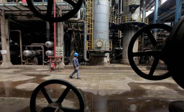 A worker walks past oil pipes at a refinery in Wuhan, Hubei province March 23, 2012. REUTERS/Stringer/File Photo