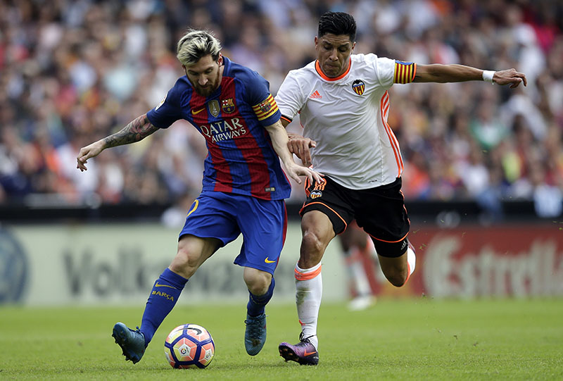 FC Barcelona's Lionel Messi (left) duels for the ball with Valencia's Enzo Perez during the Spanish La Liga soccer match between Valencia and FC Barcelona at the Mestalla stadium in Valencia, Spain, on Saturday, October 22, 2016. Photo: AP