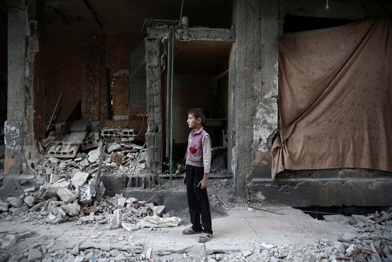 A boy stands near a damaged building after an airstrike yesterday in the rebel held Douma neighbourhood of Damascus, Syria, on Tuesday, October 4, 2016. Photo: Reuters