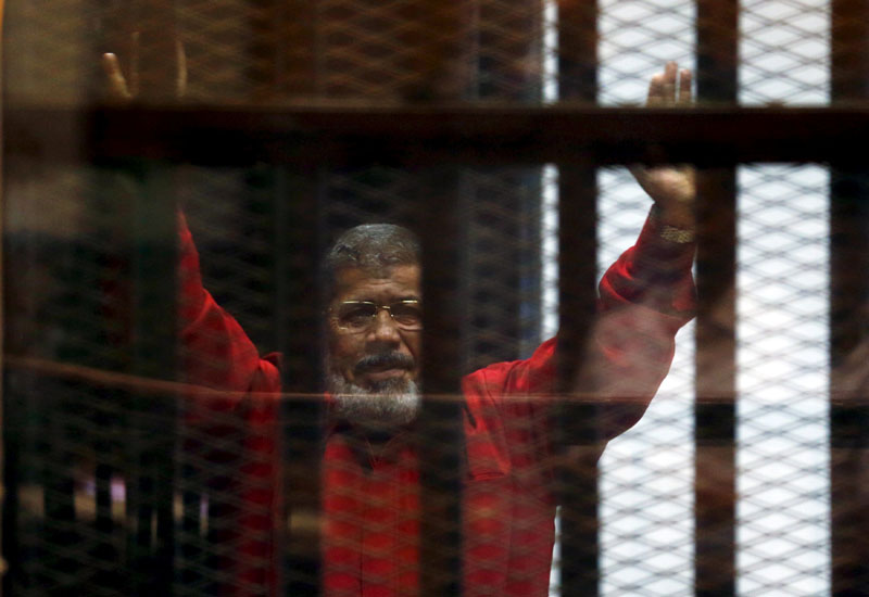 File - Egypt's deposed president Mohamed Mursi greets his lawyers and people from behind bars at a court wearing the red uniform of a prisoner sentenced to death, during his court appearance with Muslim Brotherhood members on the outskirts of Cairo, Egypt, on June 21, 2015. Photo: Reuters
