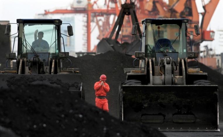 An employee walks between front-end loaders which are used to move coal imported from North Korea at Dandong port in the Chinese border city of Dandong, Liaoning province December 7, 2010. REUTERS/Stringer/File Photo