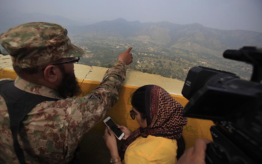 A Pakistan army officer point out the Indian forward area posts to journalists at a forward area Bagsar post on the Line of Control (LOC), that divides Kashmir between Pakistan and India, in Bhimber, some 166 kilometers (103 miles) from Islamabad, Pakistan, Saturday, Oct. 1, 2016. The latest tensions were sparked by a militant attack on an Indian army base in Kashmir that killed 18 Indian soldiers. Both countries claim the Himalayan territory Kashmir, which is split between Indian and Pakistani-controlled zones. Pakistani officials said two of their soldiers were killed and nine others were wounded in the latest exchanges at five different places along the disputed border. (AP Photo/Anjum Naveed)