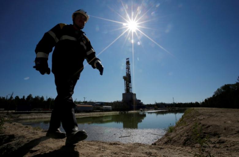 A worker walks past a drilling rig at a well pad of the Rosneft-owned Prirazlomnoye oil field outside the West Siberian city of Nefteyugansk, Russia, August 4, 2016. REUTERS/Sergei Karpukhin/File Photo