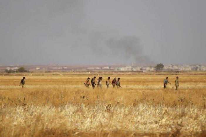 Rebel fighters in Marea city walk near rising smoke after strikes on Syria Democratic Forces (SDF) controlled Tell Rifaat town, northern Aleppo province, Syria October 21, 2016. REUTERS/Khalil Ashawi