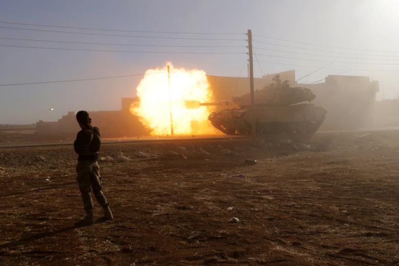 A rebel fighter stands near a Turkish tank as it fires towards Guzhe village, northern Aleppo countryside, Syria. REUTERS/Khalil Ashawi