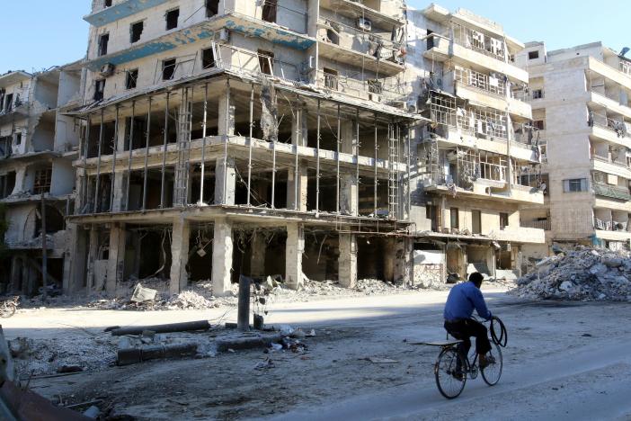 A man rides a bicycle near damaged buildings in the rebel held besieged al-Sukkari neighbourhood of Aleppo, Syria October 19, 2016. REUTERS/Abdalrhman Ismail