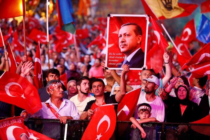 Supporters of Turkish President Recep Tayyip Erdogan wave national flags as they listen to him through a giant screen in Istanbul's Taksim Square, Turkey, August 10, 2016. REUTERS/Osman Orsal/File Photo