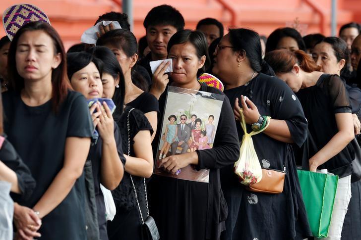 A mourner holds up a picture of Thailand's late King Bhumibol Adulyadej as she waits in line to pay respects to him outside the Grand Palace in Bangkok, Thailand, October 19, 2016. REUTERS/Chaiwat Subprasom