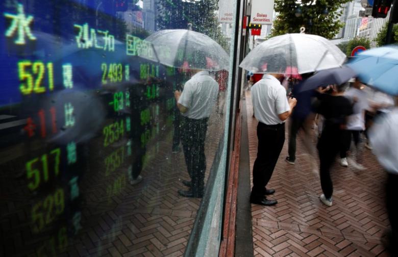 A man stands next to an electronic board showing stock prices in Tokyo, Japan, August 18, 2016. REUTERS/Kim Kyung-Hoon