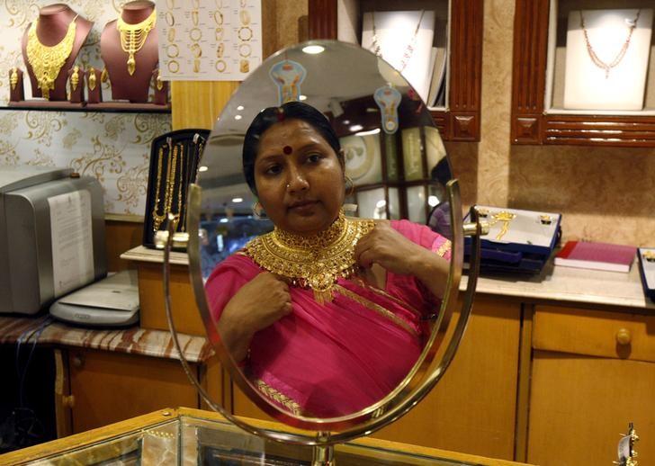 A woman is reflected in a mirror as she tries on a necklace at a jewellery showroom on Akshaya Tritiya, a major gold buying festival, in Kolkata, India, April 21, 2015. REUTERS/Rupak De Chowdhuri/File Photo