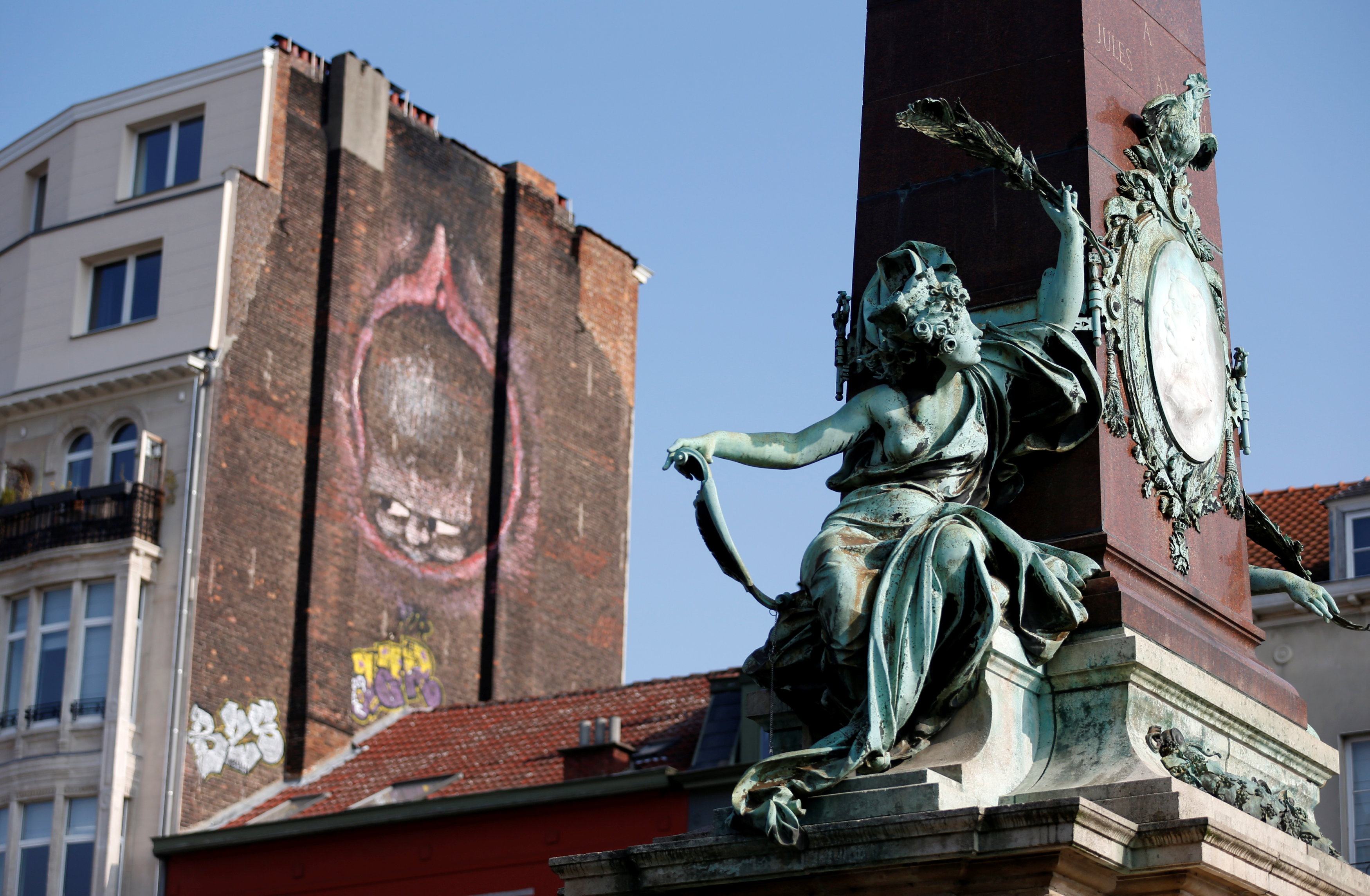 A sculpture is seen near an explicit graffiti painted on the side of a building in central Brussels, Belgium, on October 11, 2016. Photo: Reuters