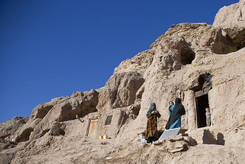 Marzia (30) in blue, talks to her neighbor near her cave in Bamiyan, Afghanistan, on Monday, November 7, 2016. Marzia and her husband Qadeer thought themselves lucky when they moved into a 1,700-year-old Buddhist cave hand-carved into the side of a mountain in Afghanistan's central highlands _ it was clean and dry, warm in the winter, cool in the summer, and there was plenty of work on the local farms. Photo: AP