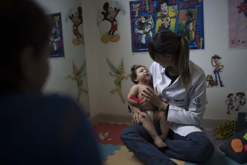File- Angelica Pereira (L) watches as her 1-year-old daughter Luiza, disabled by the Zika virus, goes through a physical therapy session at the UPAE hospital in Caruaru, Pernambuco state, Brazil, on September 27, 2016. Photo: AP