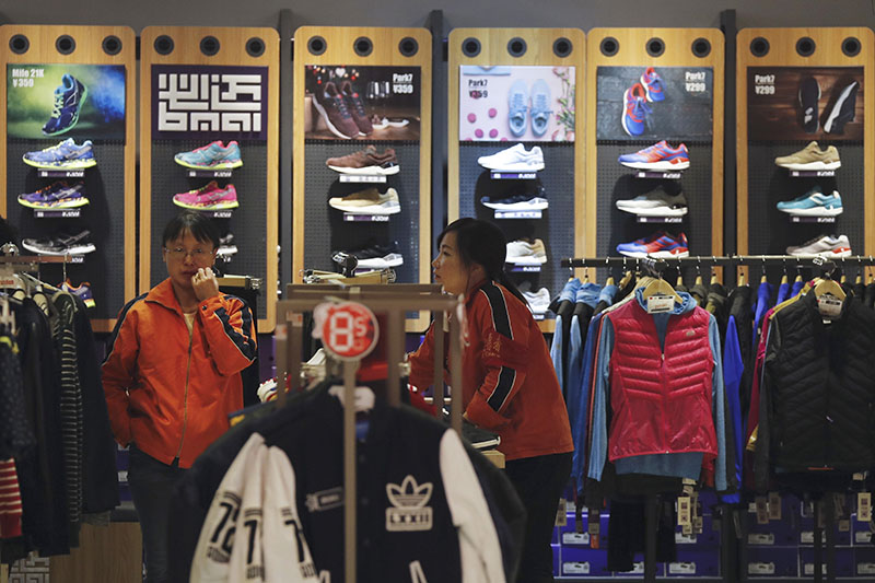Workers wait for customers at a shop selling sport wears in Beijing, on Tuesday, November 8, 2016. China's exports fell again in October in a fresh sign that weak global demand is complicating efforts by Beijing leaders to shore up economic growth and reduce reliance on trade and investment. Photo: AP