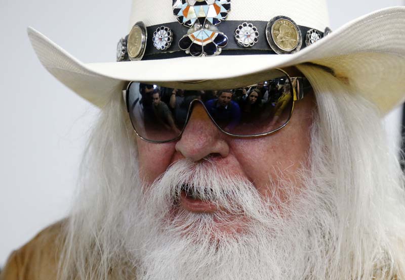 File- Reporters are reflected in the sunglasses of Leon Russell as he answers a question at a news conference in Tulsa, Okla, on January 29, 2013. Photo: AP