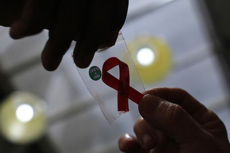 A nurse (L) hands out a red ribbon to a woman, to mark World Aids Day, at the entrance of Emilio Ribas Hospital, in Sao Paulo December 1, 2014. Photo: Reuters